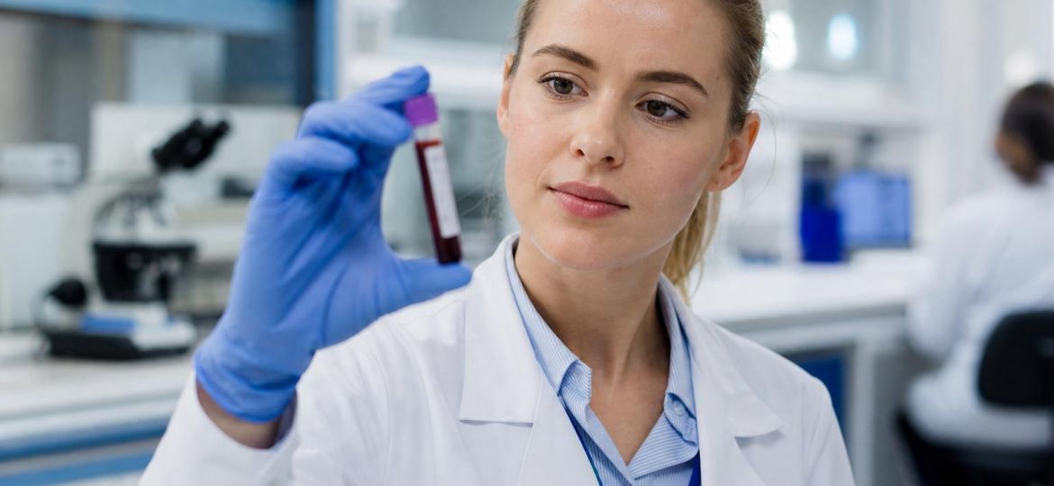 Lab technician holding a blood sample tube in a clinical laboratory