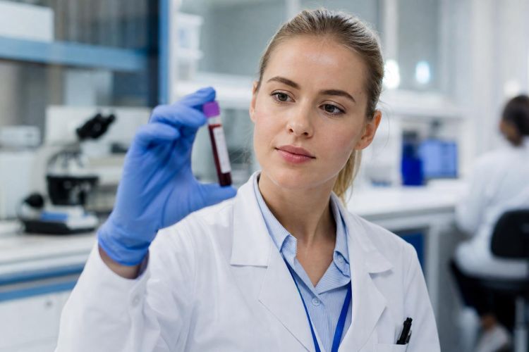 Lab technician holding a blood sample tube in a clinical laboratory