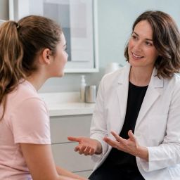 Teenager talking with a dermatologist in a bright clinic exam room