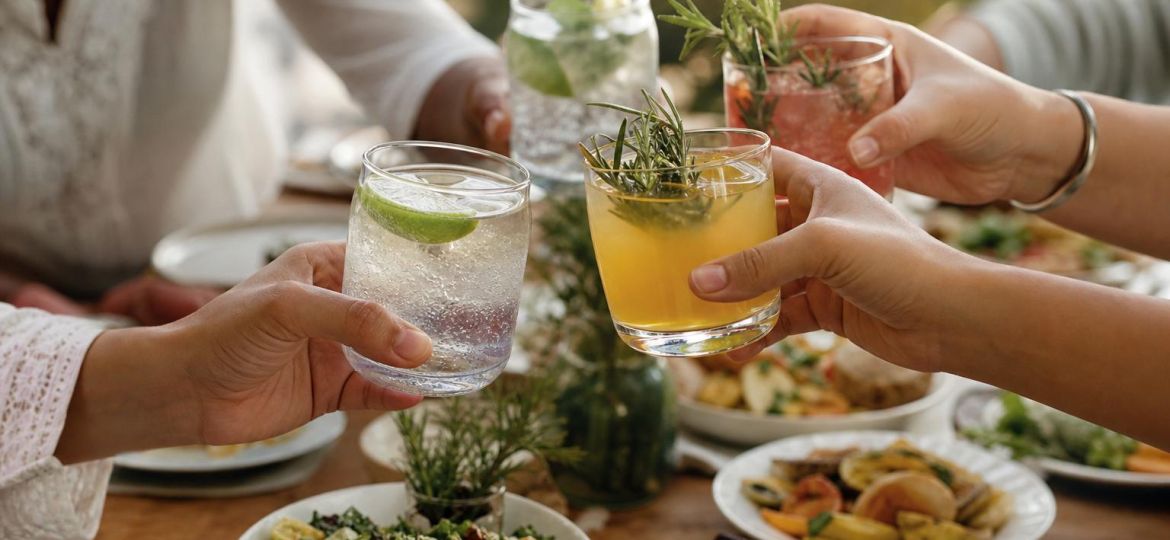Friends at dinner holding sparkling water and alcohol-free mocktails