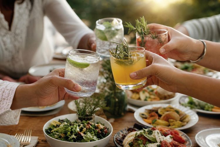 Friends at dinner holding sparkling water and alcohol-free mocktails