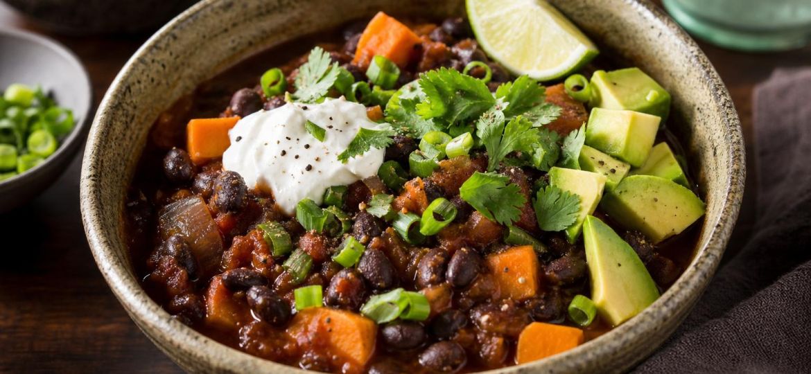 Bowl of black bean and sweet potato chili topped with avocado and cilantro