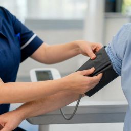 Nurse placing a blood pressure cuff on a patient's upper arm