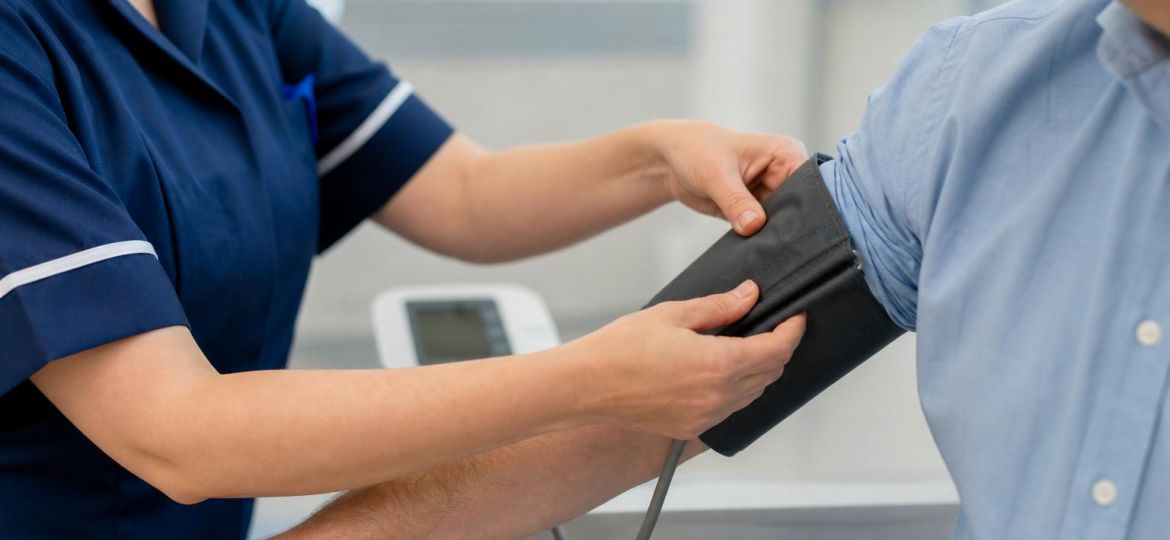Nurse placing a blood pressure cuff on a patient's upper arm