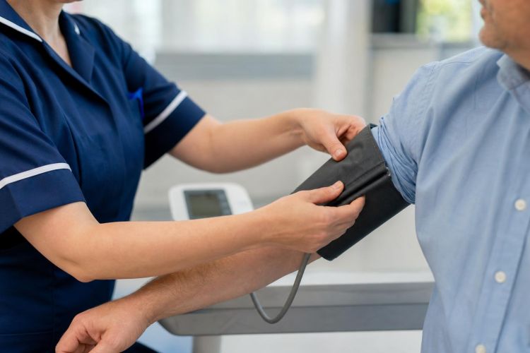 Nurse placing a blood pressure cuff on a patient's upper arm