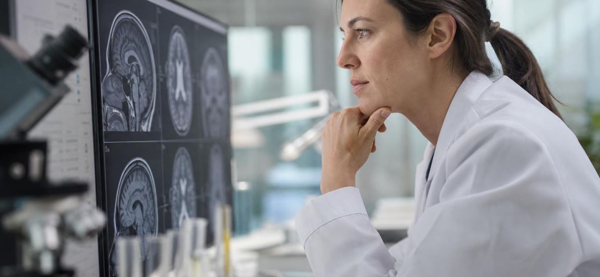 Neuroscientist in a research lab studying a brain MRI scan on a monitor