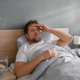 Man resting in bed with soup and water on the nightstand