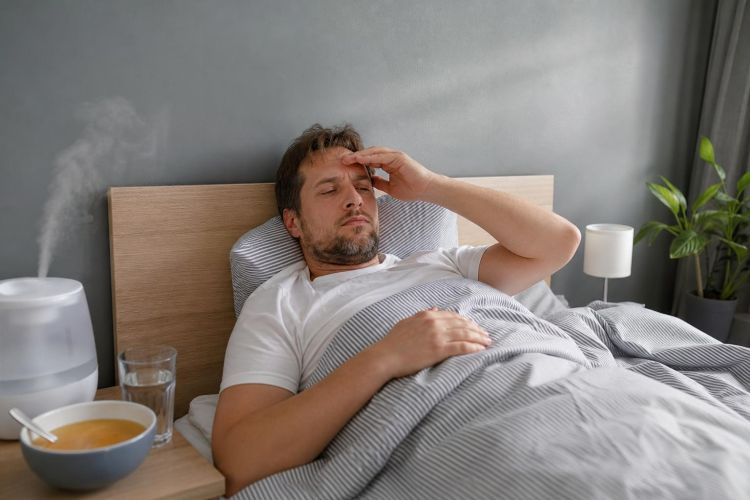 Man resting in bed with soup and water on the nightstand