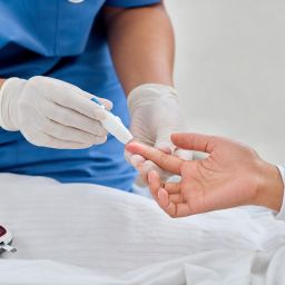 Nurse doing a finger-prick blood glucose test on a patient