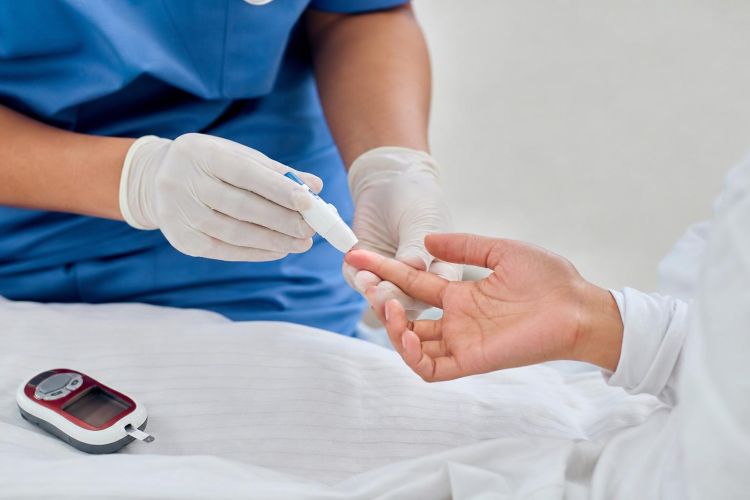 Nurse doing a finger-prick blood glucose test on a patient