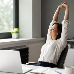 Office worker stretching her arms overhead beside her desk