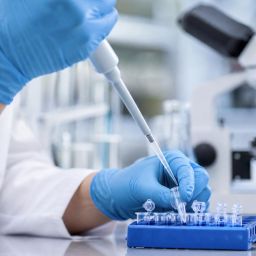 Scientist using a pipette over sample tubes in a research laboratory