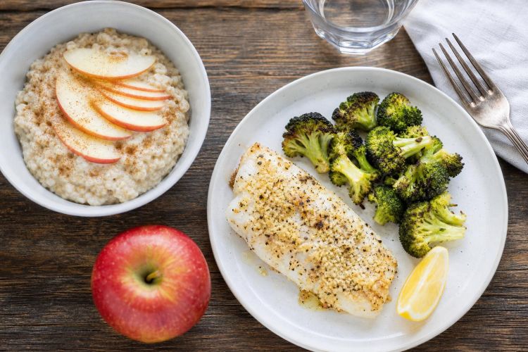 Heart-healthy meal of baked cod, roasted broccoli and oatmeal with apple slices