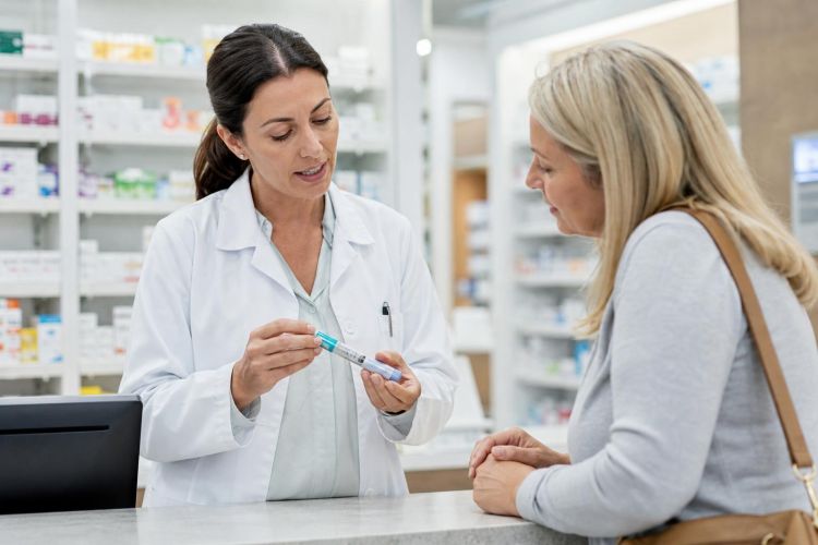 Pharmacist explaining an injection pen to a customer at a pharmacy counter