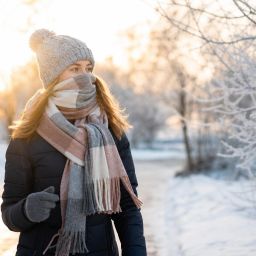 Woman walking on a winter morning with a hat, gloves and a scarf over her face