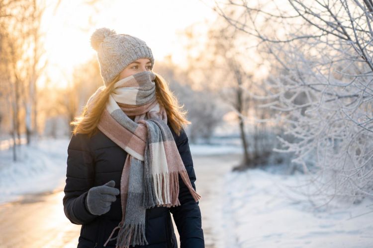 Woman walking on a winter morning with a hat, gloves and a scarf over her face