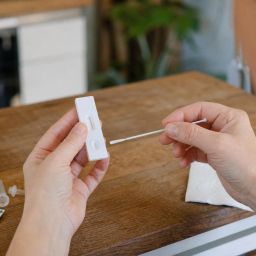 Hands using a rapid at-home antigen test with a nasal swab