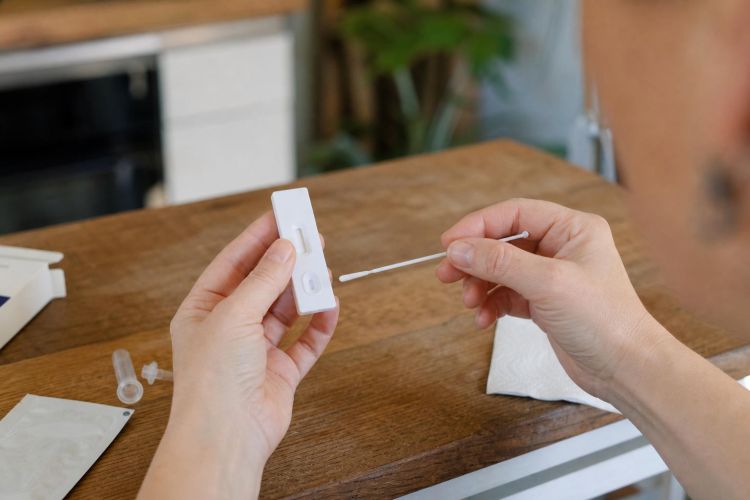 Hands using a rapid at-home antigen test with a nasal swab