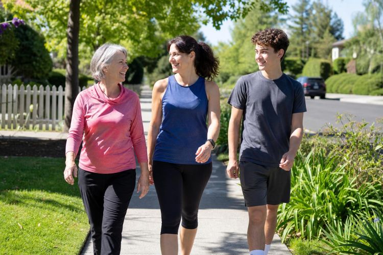 Three generations of a family walking briskly together on a sunny sidewalk
