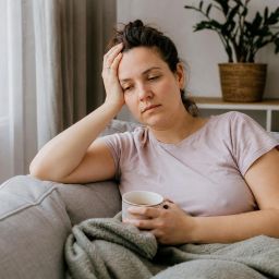 Tired woman resting on a sofa with a cup of tea