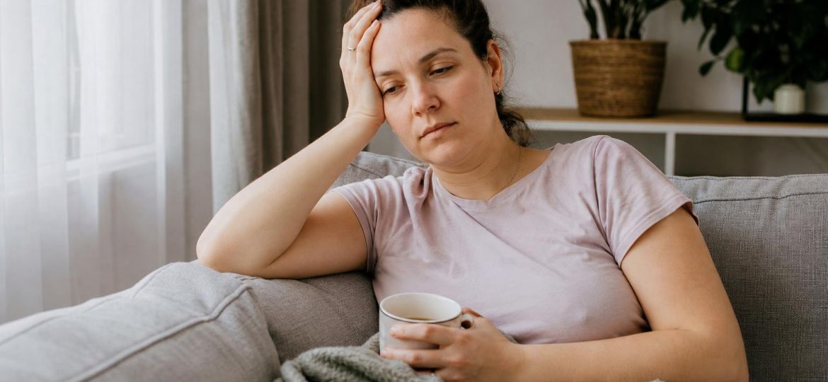 Tired woman resting on a sofa with a cup of tea