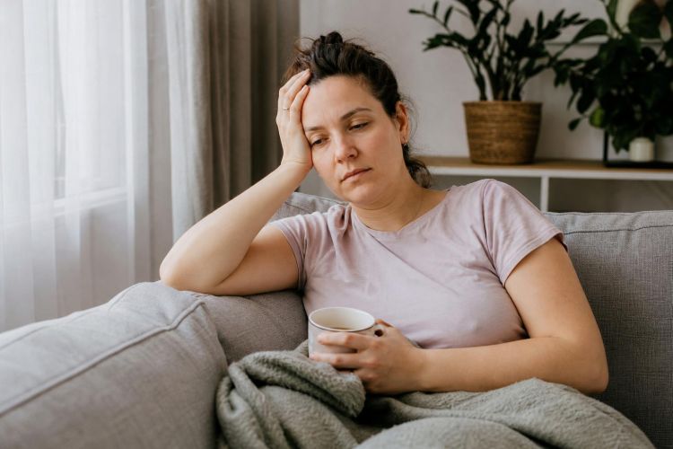 Tired woman resting on a sofa with a cup of tea