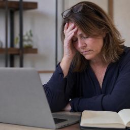 Exhausted woman sitting at a desk holding her head