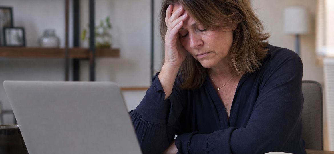 Exhausted woman sitting at a desk holding her head