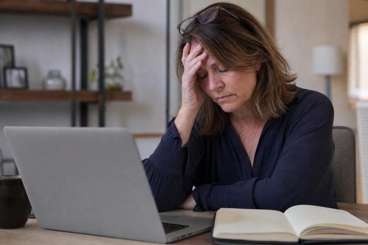Exhausted woman sitting at a desk holding her head