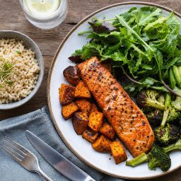 Plate of grilled salmon, avocado, salad and roasted vegetables with a bowl of brown rice