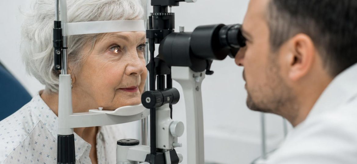 Older woman having an eye exam with an ophthalmologist at a slit-lamp microscope