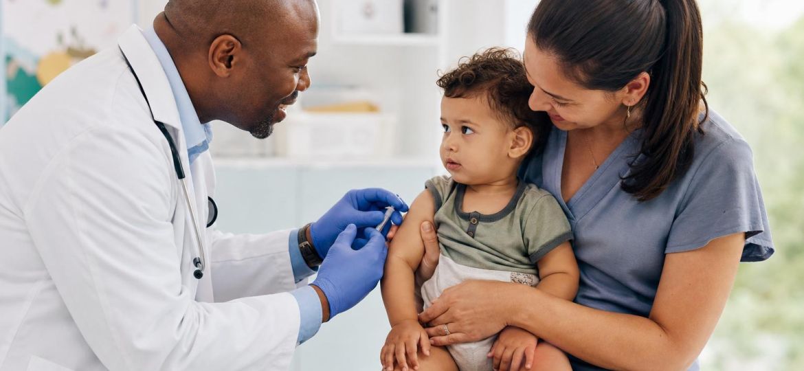 Pediatrician vaccinating a toddler sitting on a parent's lap