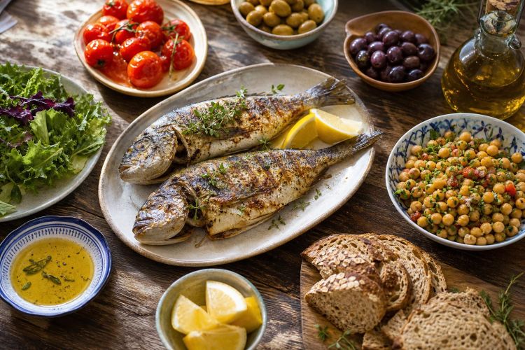 Mediterranean diet foods: fish, olive oil, tomatoes, olives, chickpeas and whole-grain bread