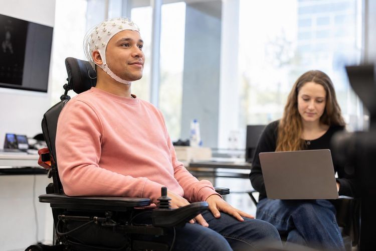 Person in a power wheelchair wearing an EEG electrode cap in a research lab