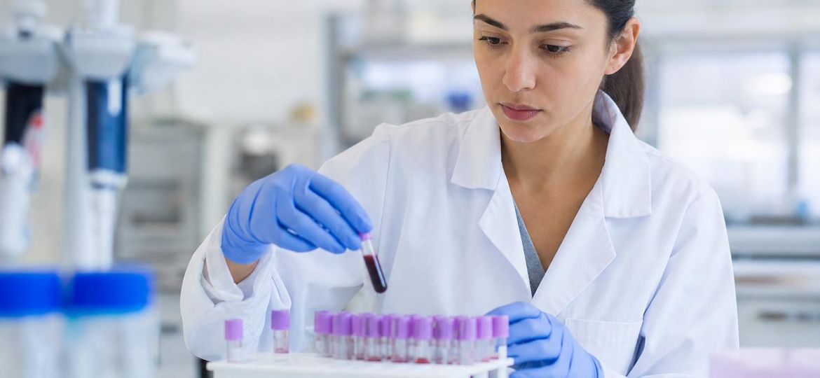 Lab technician placing blood sample tubes into a rack in a research lab