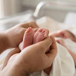 Newborn baby's tiny feet held gently in a parent's hands