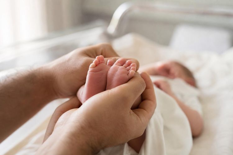 Newborn baby's tiny feet held gently in a parent's hands