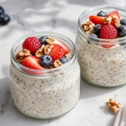 Jars of overnight oats topped with berries, chia seeds and walnuts