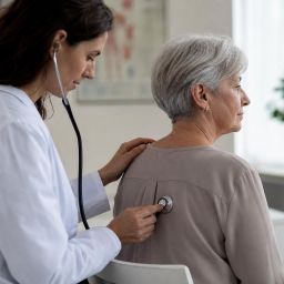Doctor listening to an older woman's lungs with a stethoscope