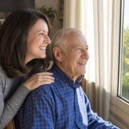 Adult daughter visiting her elderly father by an open sunny window