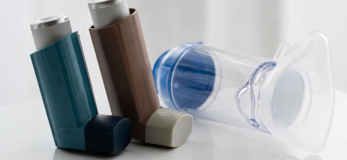 Two asthma inhalers and a spacer on a white table