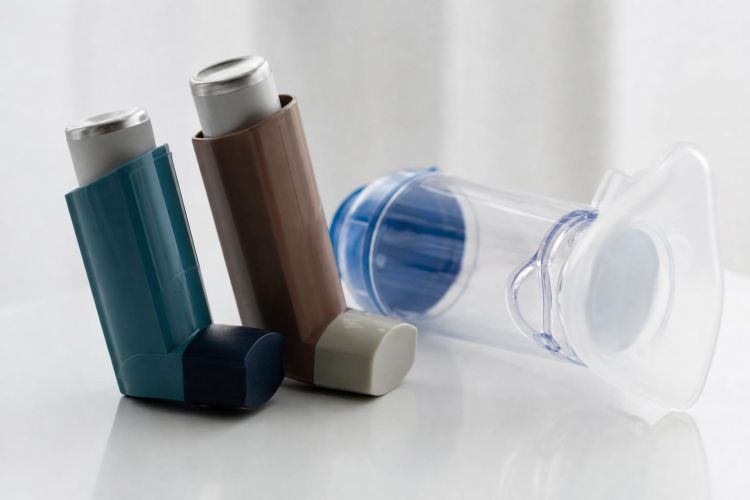 Two asthma inhalers and a spacer on a white table