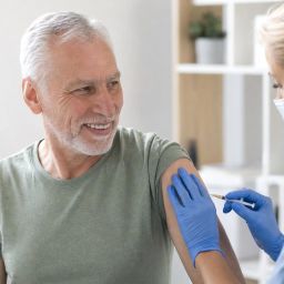 Man in his sixties receiving a vaccine from a nurse