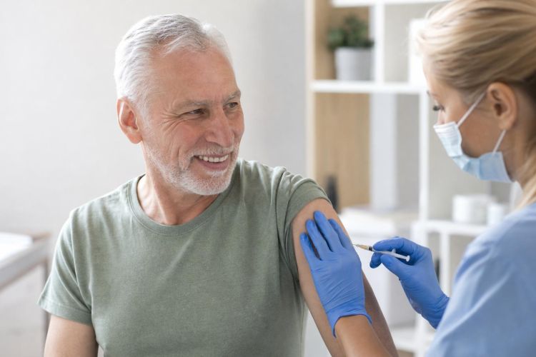 Man in his sixties receiving a vaccine from a nurse