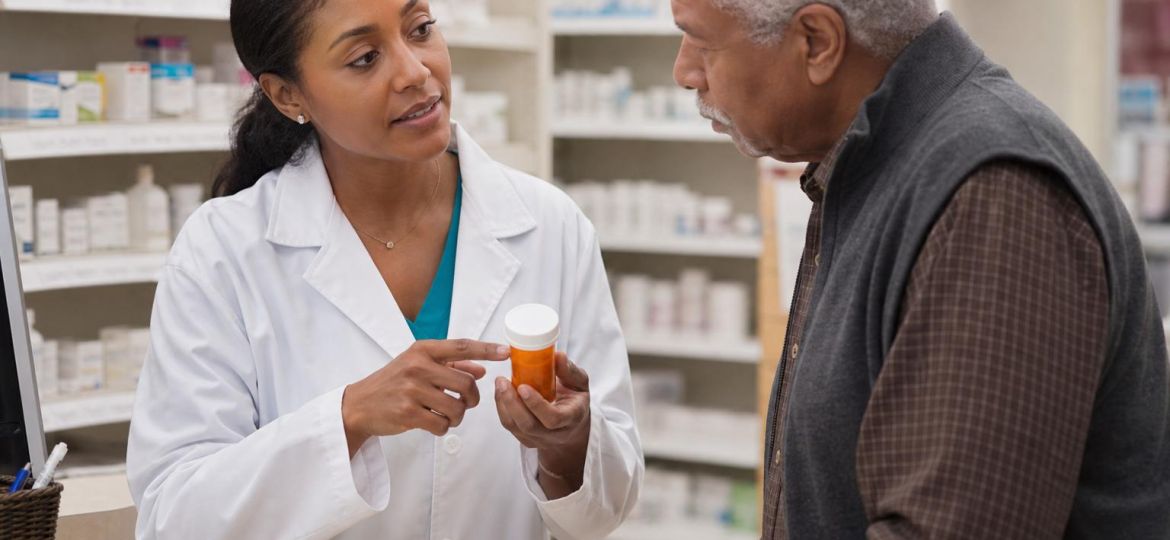 Pharmacist explaining a prescription to an older man at a pharmacy counter