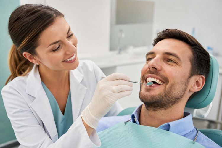 Dentist examining a smiling patient's teeth in a modern dental office