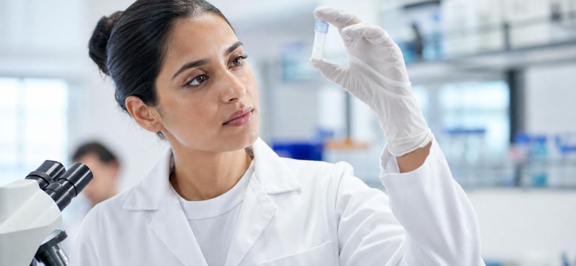 Virologist in a lab holding up a sample tube